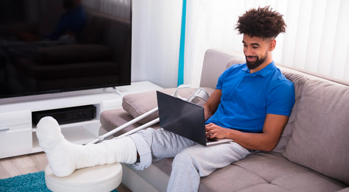 Un jeune homme avec la jambe dans le plâtre consulte nos dispositifs sur le site Lourmel.