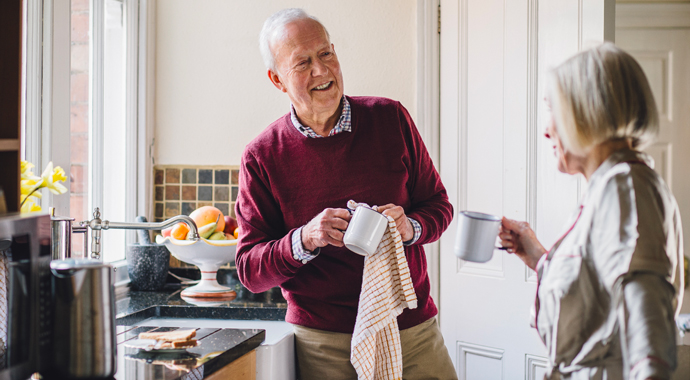 Un couple de retraite en conversation nettoient des mug dans leur cuisine