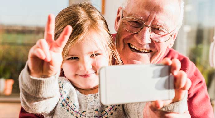 Petite fille et son grand-père faisant un selfie avec le téléphone du grand-père qui veux rester dynamique et dans l'ère du temps