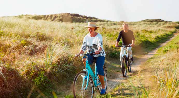 Un couple fait joyeusement une promenade en vélo dans une prairie