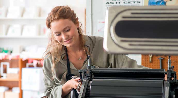 Une femme réglant une machine d'impression dans son atelier