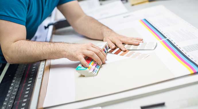 un imprimeur contrôle la colorimétrie d'un document avec son pantone