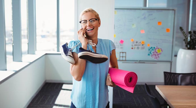 Femme au téléphone active repliant son tapis de gymnastique