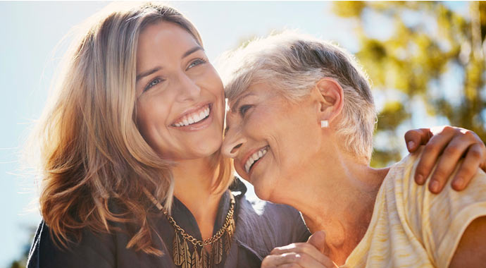 Une femme et sa mère s'enlacent et rient aux éclats.