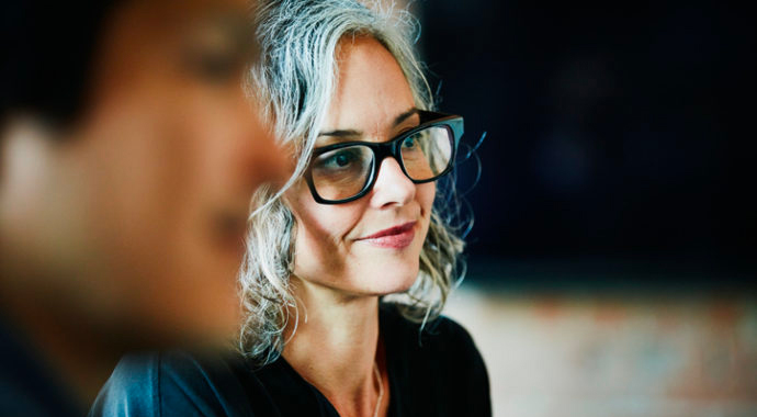 Femme avec des lunettes souriante durant une réunion concernant la santé