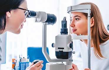 Jeune femme avec la tête immobilisé se fait examiner la vue par une opticienne