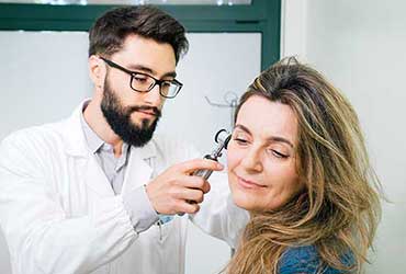 Un audiologiste examine l'oreille d'une patiente