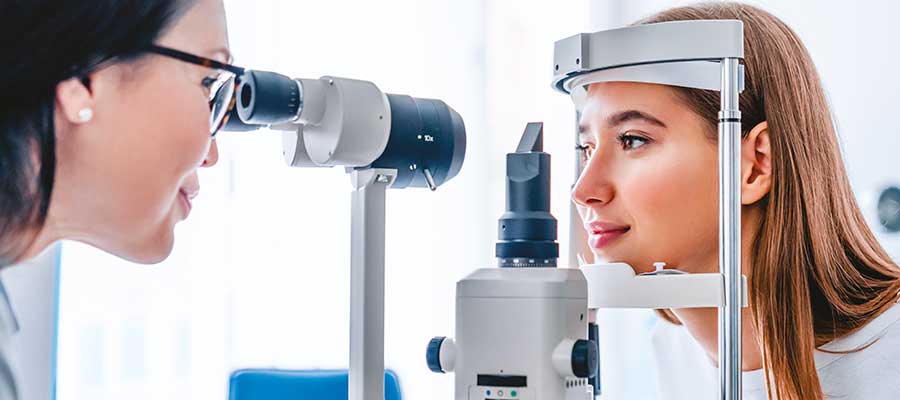 Jeune femme avec la tête immobilisé se fait examiner la vue par une opticienne